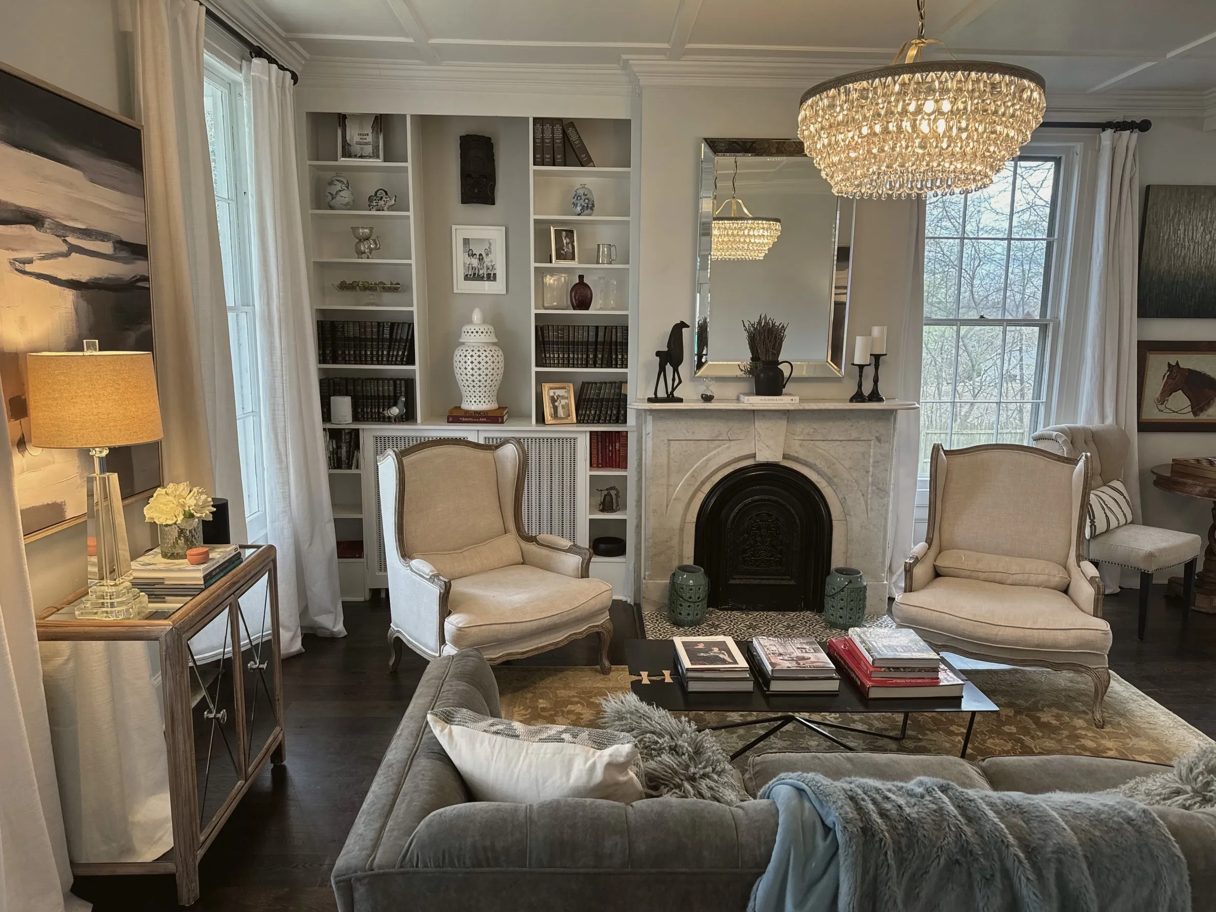 The parlor — crystal chandelier, marble fireplace, full bookshelves